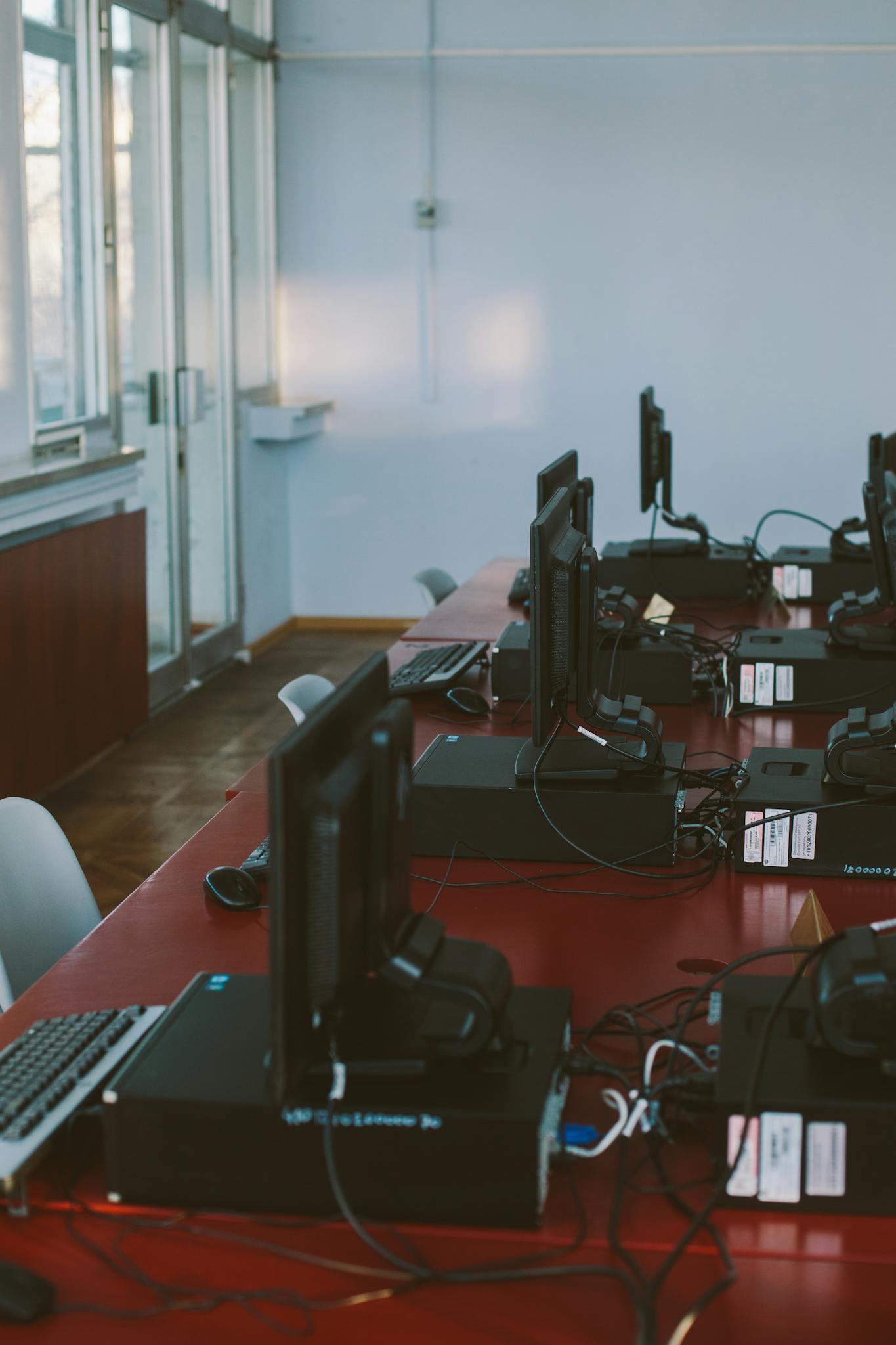 Interior of a computer lab with desktops on a conference table, featuring natural light.