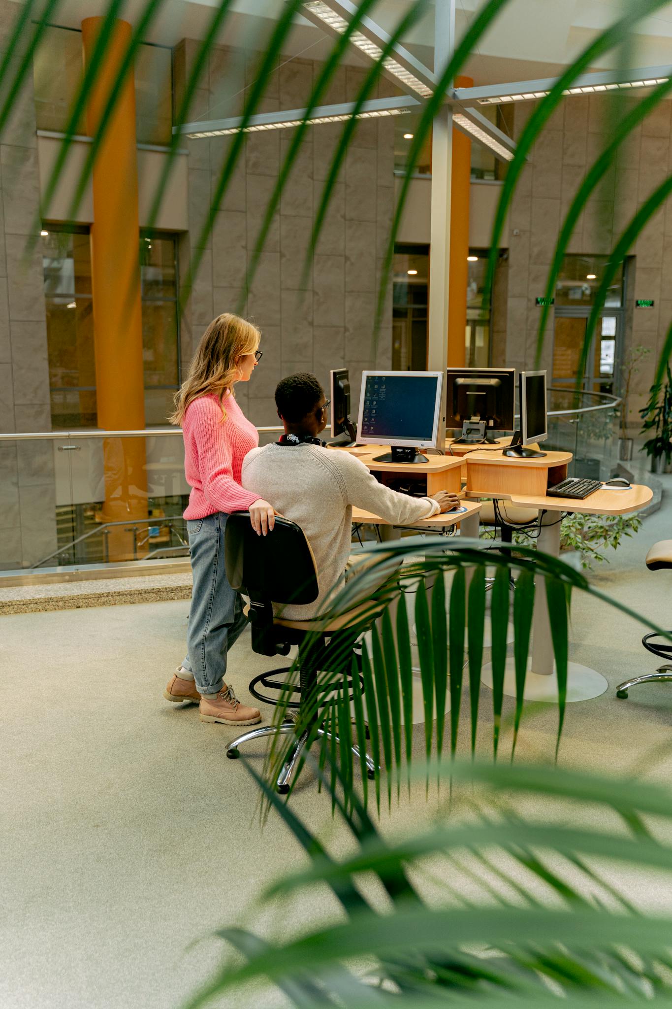 Two colleagues working together in a bright and modern indoor office setting.